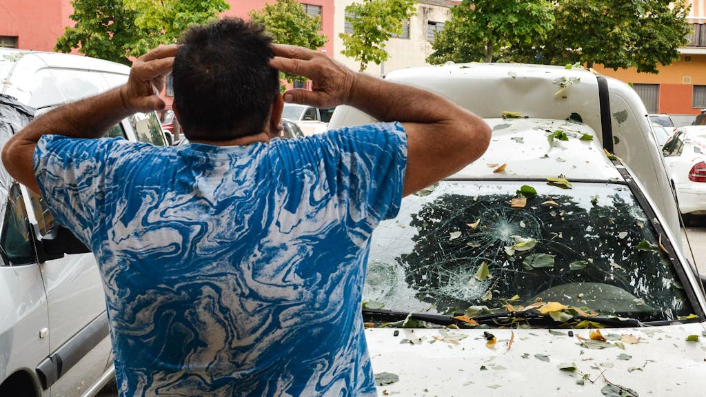 Ein Mann betrachtet sein Auto, das von dem Hagelsturm beschädigt wurde, welcher am Dienstag (30. August) über Katalonien hereingebrochen ist.