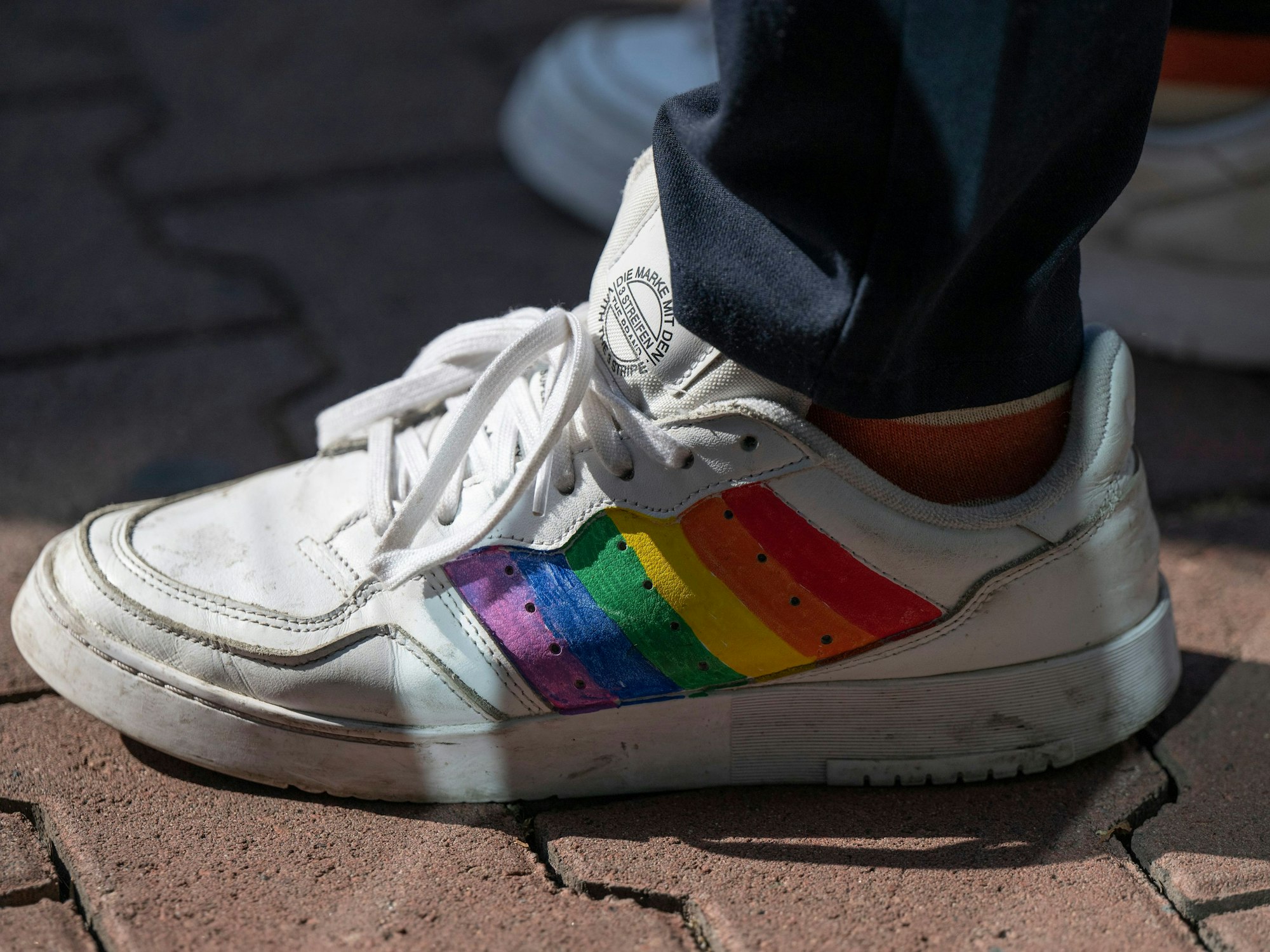 Das Foto von August 2022 zeigt einen weißen Sneaker, auf den die Regenbogenflagge als Erkennungszeichen der LGBTQI+-Community gemalt wurde.
