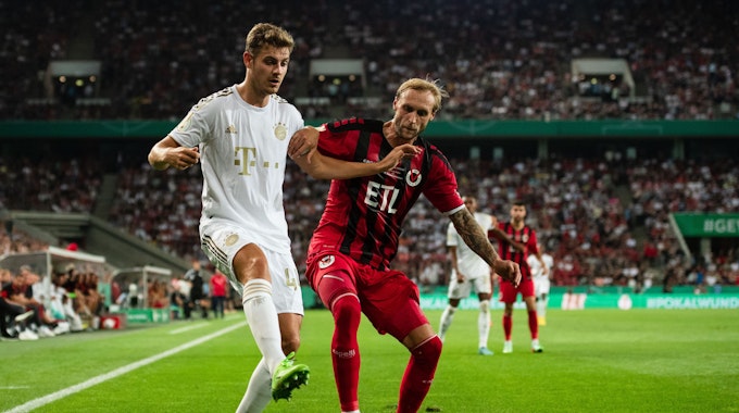 Bayerns Josip Stanisic (l) und Kölns Marcel Risse kämpfen um den Ball.