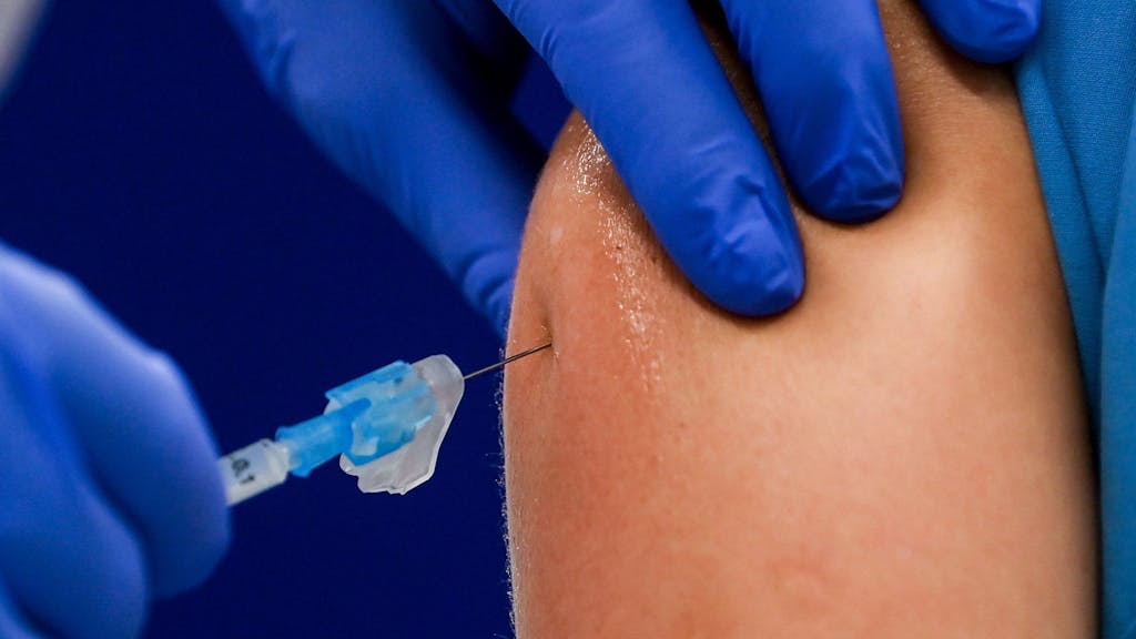 Ein Impfstoff wird in einen Oberarm injiziert.