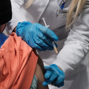 Eine Ärzten hält eine Spritze neben dem Arm einer Patientin.