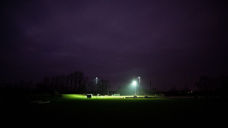 Eine Fußballmannschaft trainiert bei Flutlicht auf einem Sportplatz.