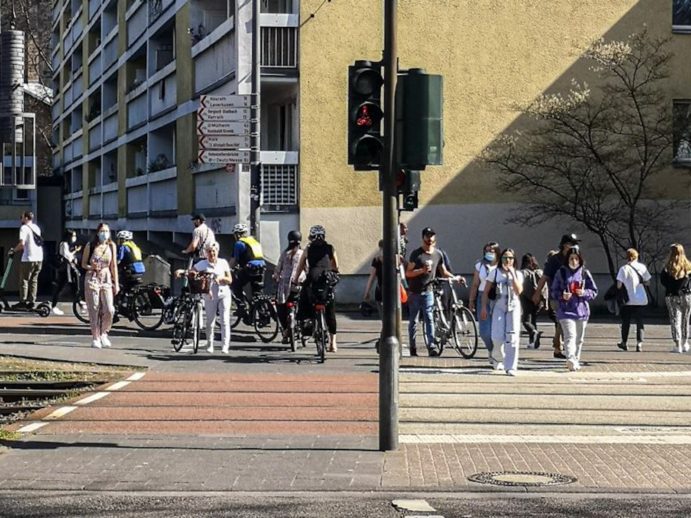 Menschen überqueren in Köln-Deutz die Siegburger Straße. Die Stadt ersetzt einen Autostreifen durch einen Radstreifen.
