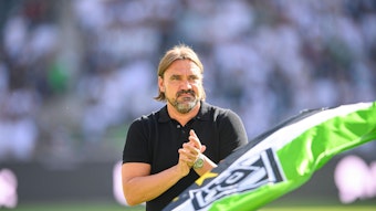 Trainer Daniel Farke bedankt sich nach dem Spiel von Borussia Mönchengladbach gegen die TSG Hoffenheim am 6. August 2022 bei den Fans im Borussia-Park. Farke applaudiert, im Vordergrund ist eine Fahne in den Gladbacher Vereinsfarben zu sehen.
