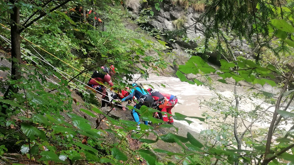 Retter arbeiten am 3. September 2022 an einem Steilhang am Flussufer. Eine Frau wurde vermisst, nachdem ihre Gruppe beim sogenannten Canyoning in der Starzlachklamm bei Sonthofen (Landkreises Oberallgäu) von einer Sturzflut überrascht wurde.