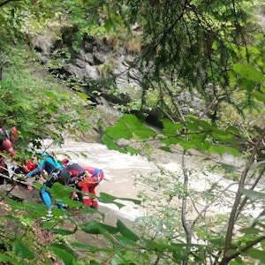 Retter arbeiten am 3. September 2022 an einem Steilhang am Flussufer. Eine Frau wurde vermisst, nachdem ihre Gruppe beim sogenannten Canyoning in der Starzlachklamm bei Sonthofen (Landkreises Oberallgäu) von einer Sturzflut überrascht wurde.