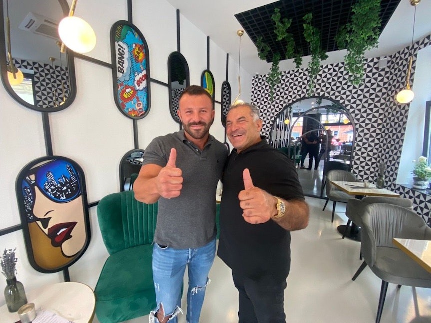 Tanju Firat und Vater Yahya stehen im Café, das der Sohn in Köln aufgebaut hat.