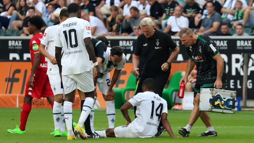 Alassane Plea sitzt angeschlagen auf dem Rasen des Borussia-Parks. Der Franzose musste das Bundesliga-Match gegen Mainz (4. September 2022) vorzeitig verletzt beenden. Der Mannschafts-Arzt eilt zur Hilfe.