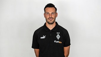 Christopher John, Co-Trainer von Fußball-Bundesligist Borussia Mönchengladbach in der Saison 2022/2023. Er hat die Arme hinter seinem Rücken verschränkt.