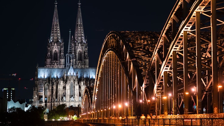 Das Foto zeigt den beleuchteten Dom und die Hohenzollern Brücke.