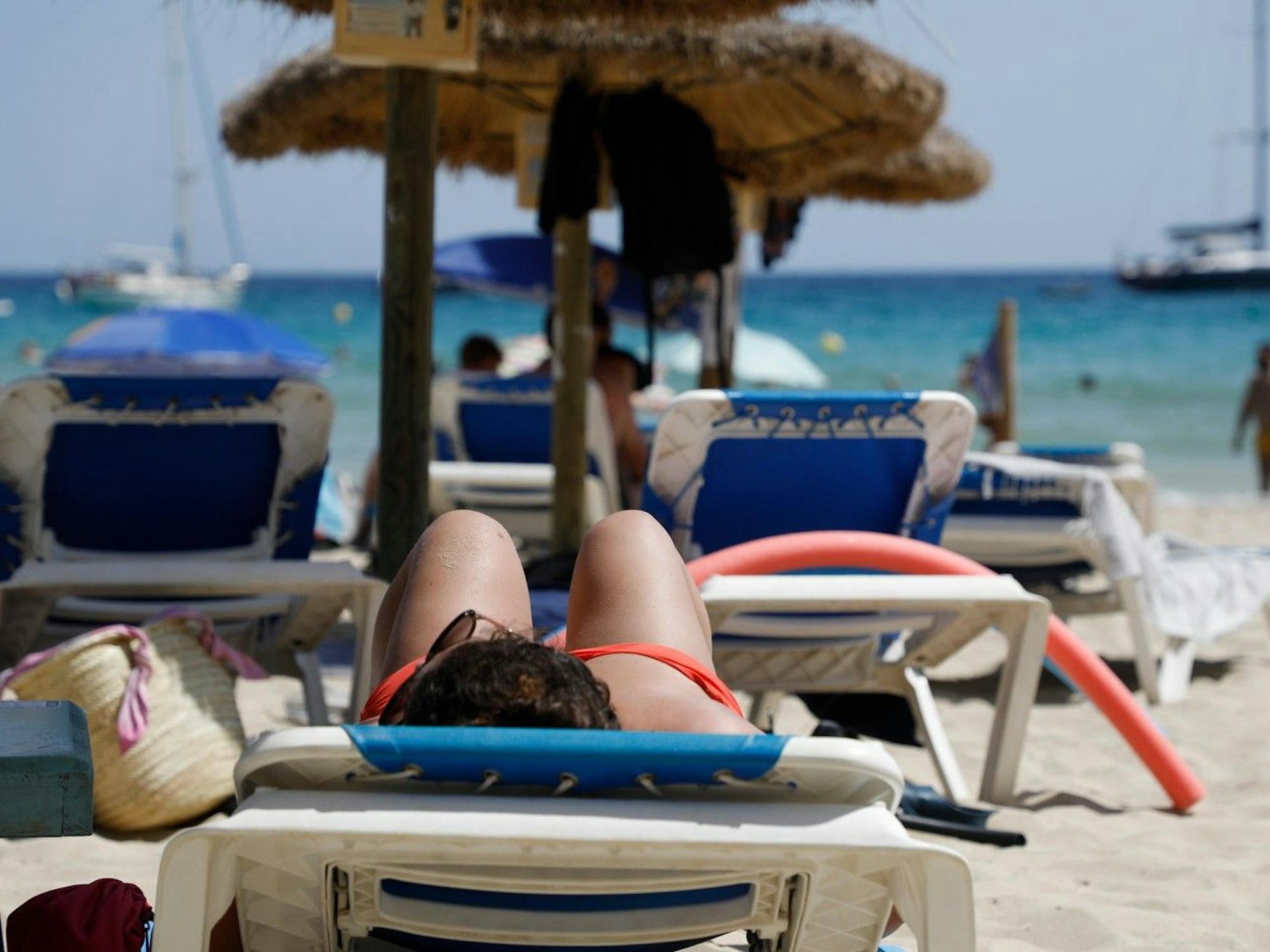 Menschen liegen im Juli 2022 am Strand von Cala Major, in der Nähe von Palma auf Mallorca, oder halten sich im Wasser auf.