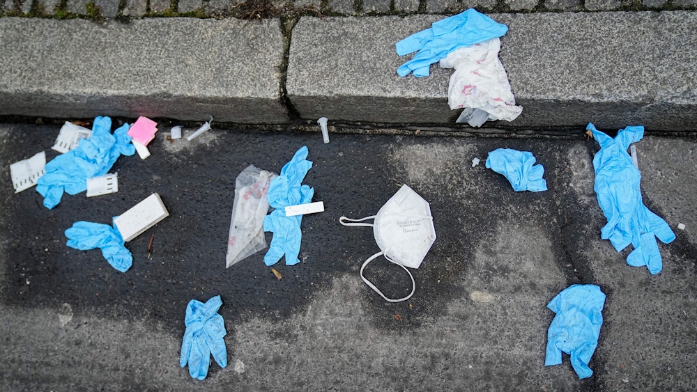 Auf dem Symbolfoto von Januar 2022 sieht man blaue Einweghandschuhe, eine FFP2-Maske und sonstigen Müll, der auf der Straße liegt.