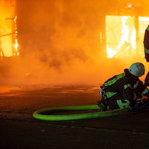 Feuerwehrleute löschen den Brand einer Lagerhalle.