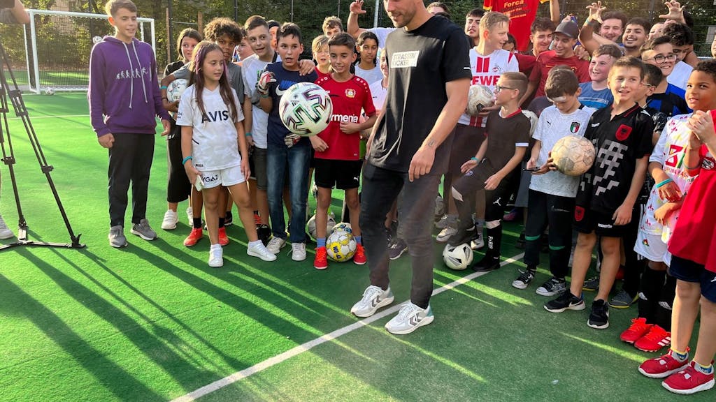 Lukas Podolski hält den Ball hoch.