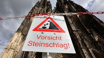 Ein Schild vor dem Kölner Dom mit dem Warnhinweis: Vorsicht Steinschlag!