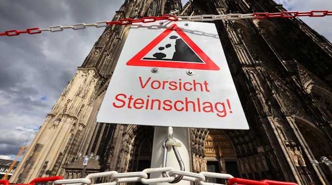 Ein Schild vor dem Kölner Dom mit dem Warnhinweis: Vorsicht Steinschlag!