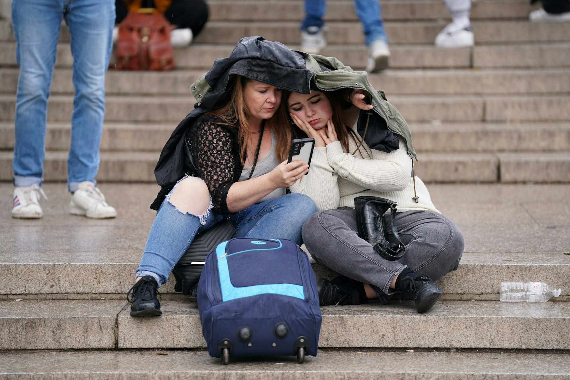 Zwei Frauen verfolgen auf dem Smartphone die aktuellen Nachrichten rund um den Gesundheitszustand der Königin.