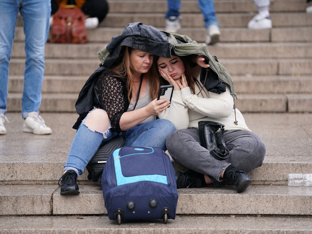 Zwei Frauen verfolgen auf dem Smartphone die aktuellen Nachrichten rund um den Gesundheitszustand der Königin.