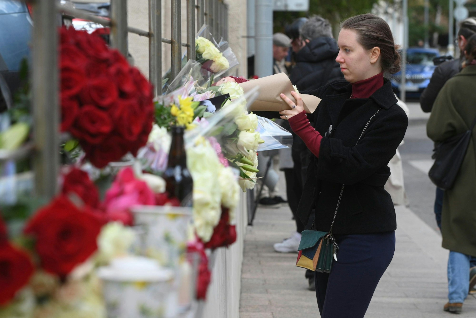 Eine junge Frau bringt am Freitag, 9. September 2022, Blumen zur britischen Botschaft in Moskau.