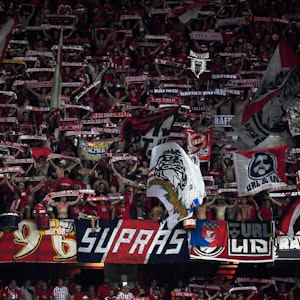 Fans des 1. FC Köln halten in der Kurve beim Spiel in Nizza ihre Schals in die Höhe