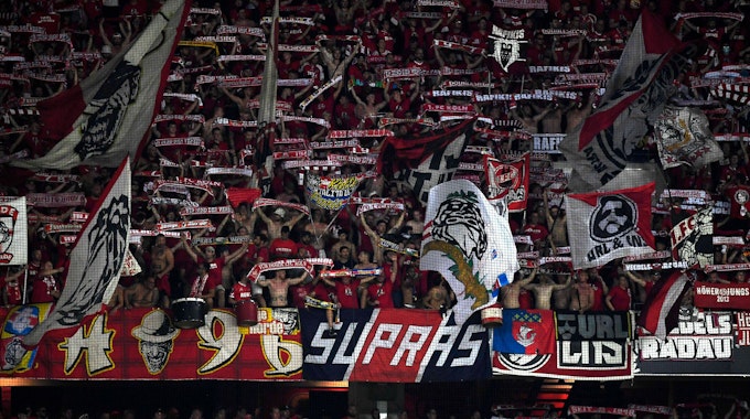 Fans des 1. FC Köln halten in der Kurve beim Spiel in Nizza ihre Schals in die Höhe
