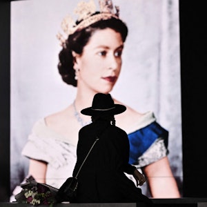 Trauer um die Queen in London: Eine Britin legt am Samstag (10. September) Blumen vor dem Konterfei Elizabeth II. ab.