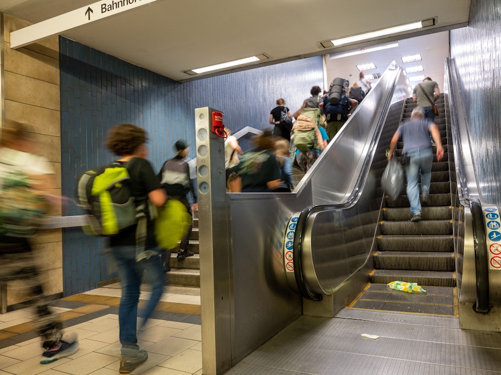 Menschen gehen am Kölner Hauptbahnhof eine Treppe hoch.