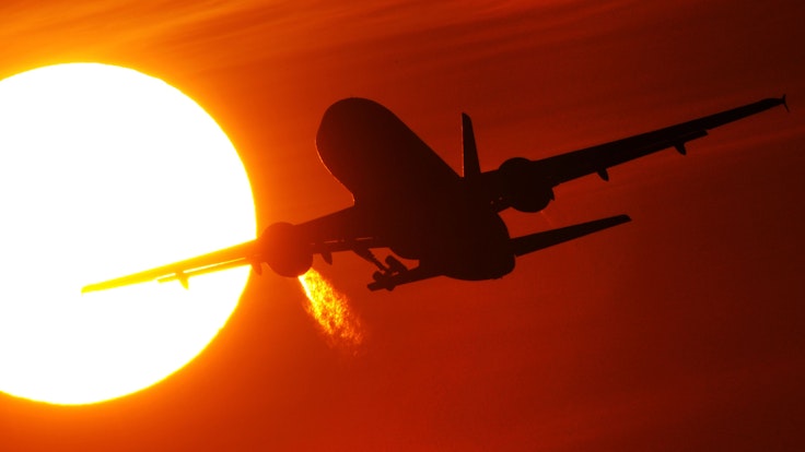 Ein Flugzeug startet am 08. Februar 2011 vom Düsseldorfer Flughafen vor der Kulisse eines spektakulären Sonnenuntergangs.