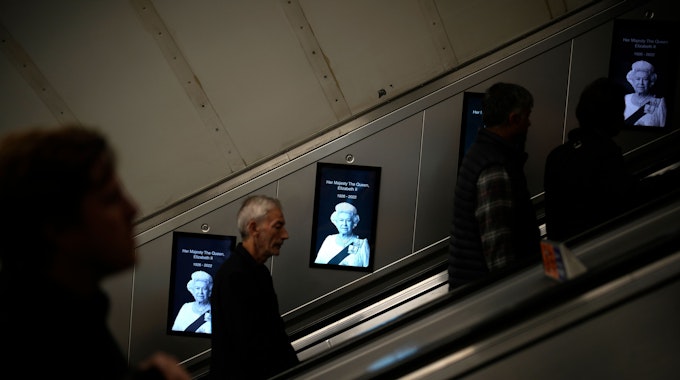 Pendler gehen in der Londoner U-Bahn an Fotos von Königin Elizabeth II. vorbei.