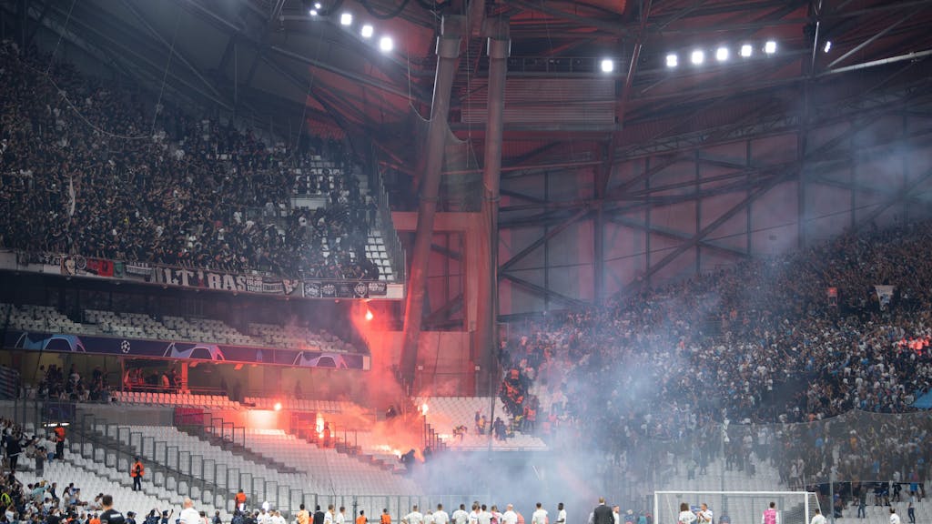 Die Blöcke der Ultras der Eintracht (l) und von Marseille beschießen sich mit Feuerwerk.