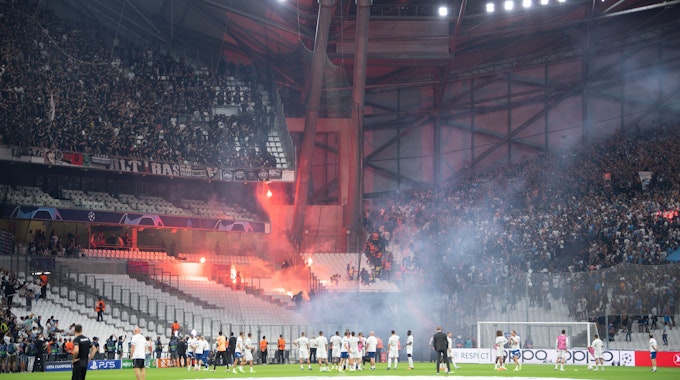 Die Blöcke der Ultras der Eintracht (l) und von Marseille beschießen sich mit Feuerwerk.