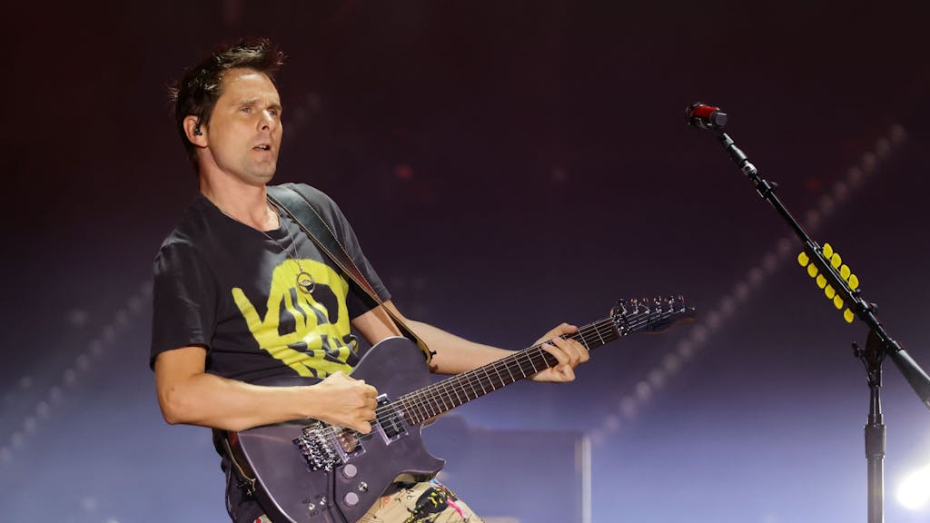 Frontmann Matthew Bellamy von Muse spielt Gitarre auf der Bühne.