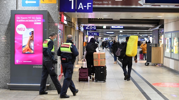 Reisende und Sicherheitskräfte gehen im Hauptbahnhof durch einen Gang zu den Bahnsteigen.