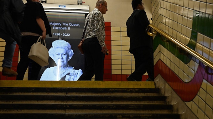 Passanten laufen am 9. September 2022 an einem Bild der verstorbenen Königin in der Londoner U-Bahn vorbei.
