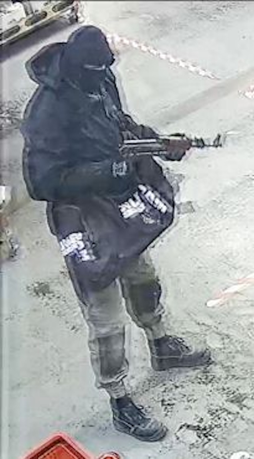 Ein vermummter Mann hält ein Sturmgewehr in den Händen.