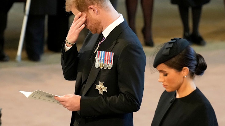 Das Foto vom 14. September 2022 zeigt Prinz Harry und seine Frau Meghan in Westminster Hall. Beide sind schwarz gekleidet und trauern.
