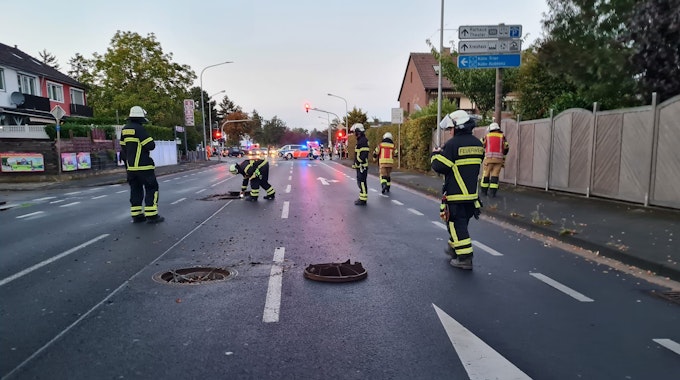 Einsatzkräfte der Feuerwehr Euskirchen begutachten die Lage am Rüdesheimer Ring. Gullydeckel liegen auf der Straße.