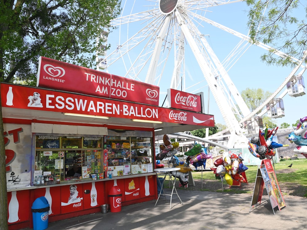Büdchen mit Luftballons und Deko vor dem Riesenrad und dem Haupteingang des Kölner Zoos.