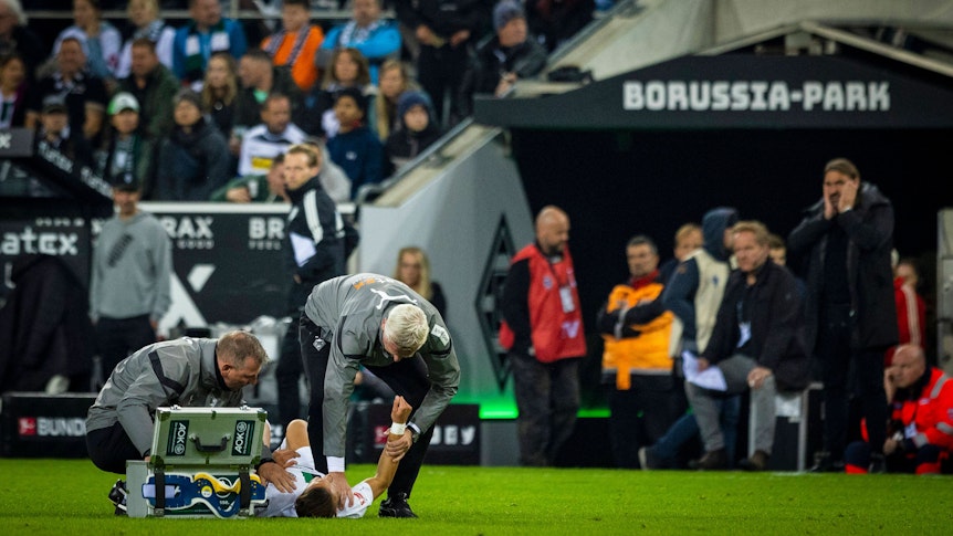 Physiotherapeut Dirk Müller (l). und Mannschaftsarzt Stefan Hertl (r.) kümmern sich um Hannes Wolf (Mitte) von Borussia Mönchengladbach.