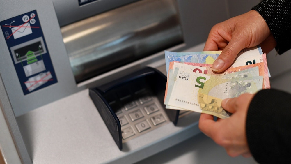 Die steigenden Preise zwingen viele Haushalte dazu, ihr Erspartes aufzubrauchen. Eine Frau hebt in unserem Symbolbild in einer Bankfiliale Geld am Automaten ab.