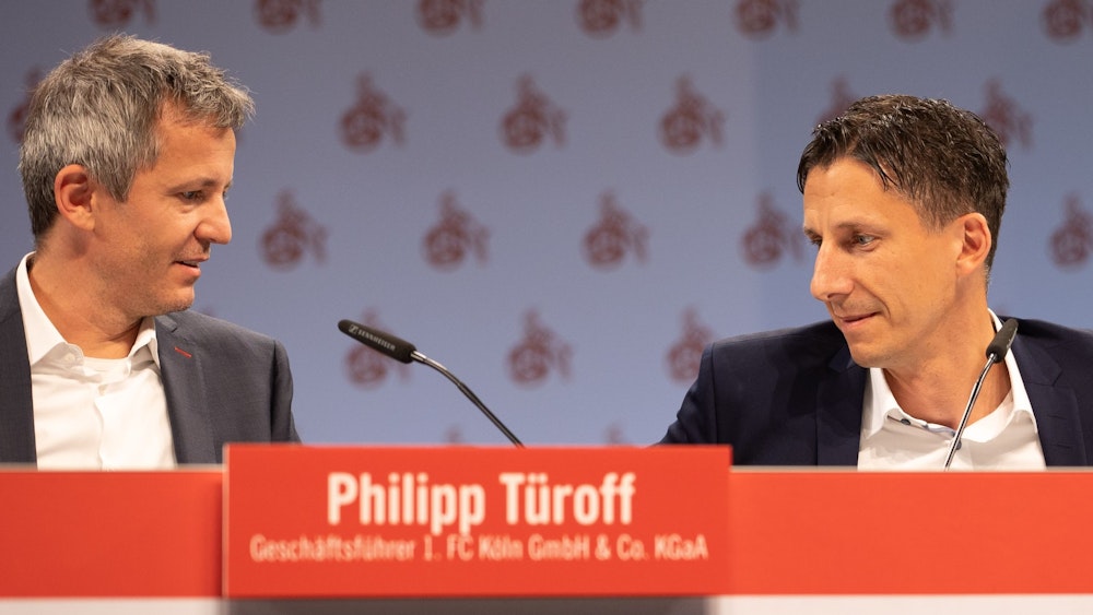 Philipp Türoff und Christian Keller sitzen bei der Mitgliederverammlung des 1. FC Köln auf dem Podium.