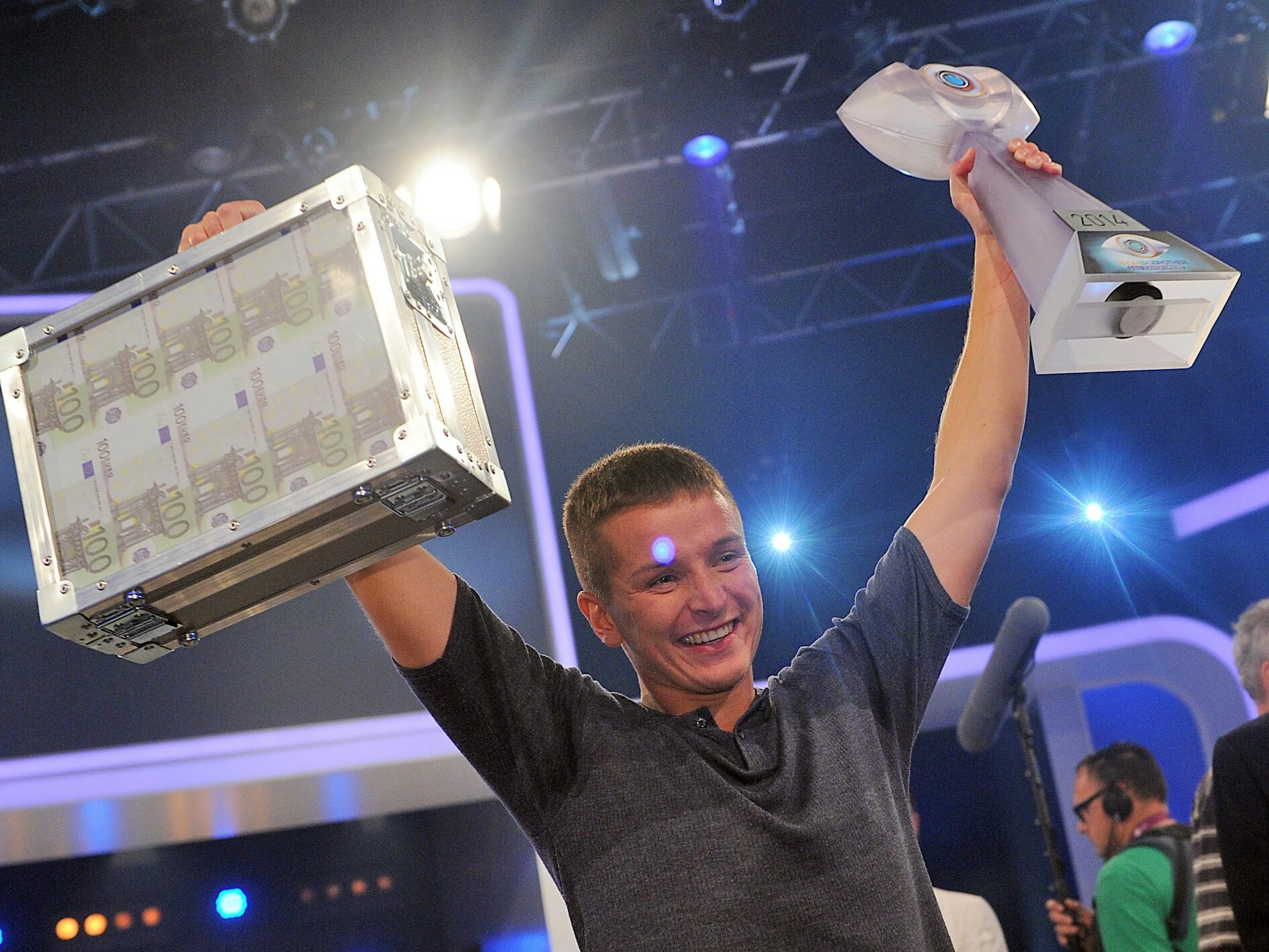 Aaron Troscke freut sich über einen Geldkoffer in Höhe von 100.000 Euro, die der einstige „Wer wird Millionär?“-Kandidat auf dem Foto überglücklich in die Luft hält.