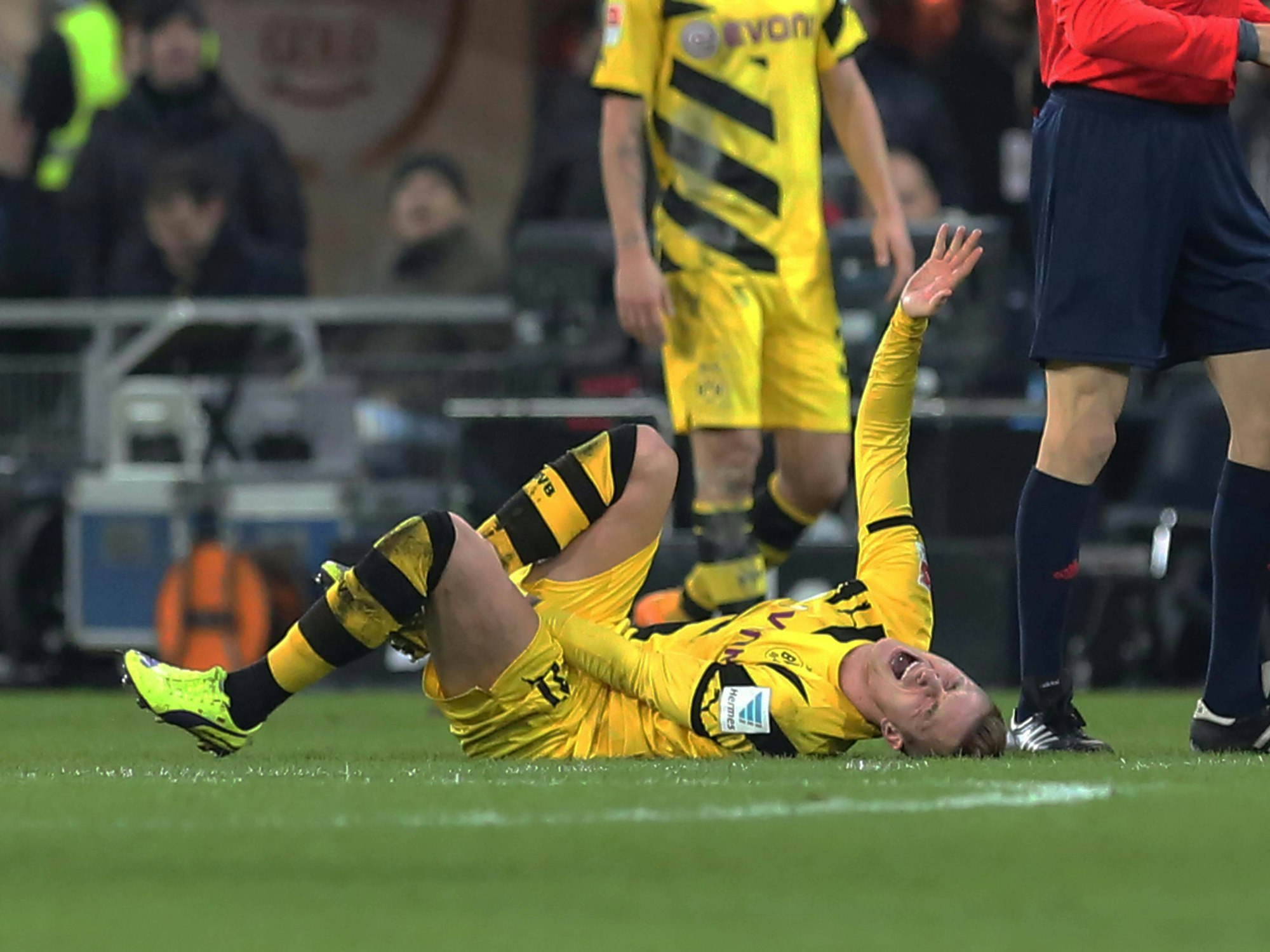 Marco Reus liegt verletzt am Boden und hält sich das rechte Sprunggelenk