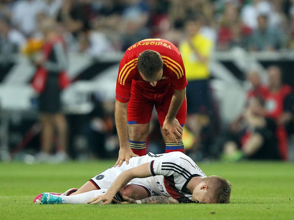 Marco Reus liegt verletzt am Boden, ein armenischer Nationalspieler blickt besorgt zu ihm herab