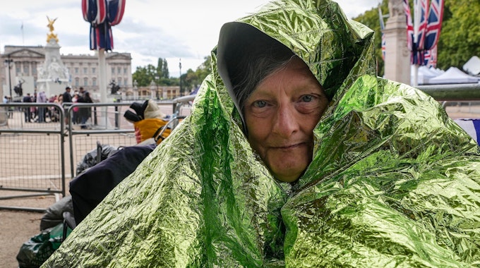Caryll Foster hält sich mit einer Rettungsdecke warm, da sie über Nacht bleiben wird, um in der ersten Reihe bei den Trauerfeierlichkeiten der Königin in der Mall vor dem Buckingham Palace sitzen will.