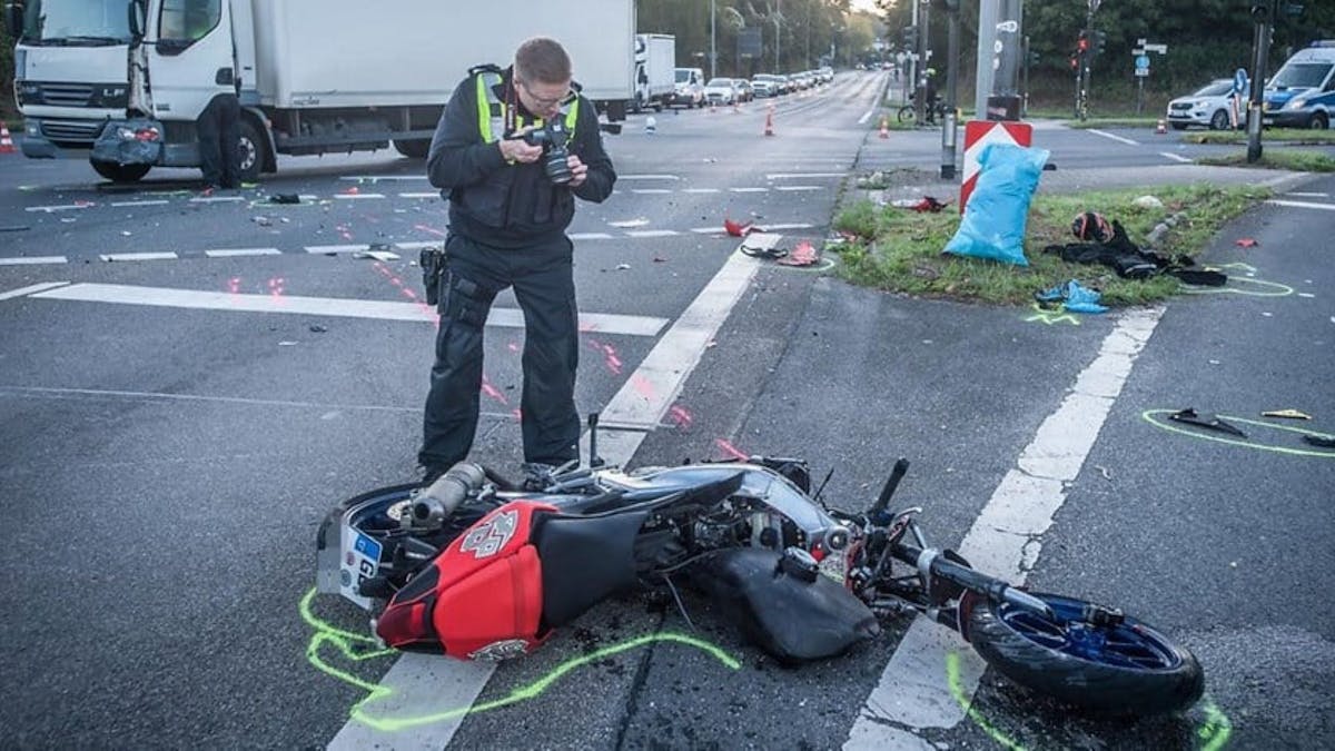 Nach einem Unfall in Leverkusen fotografiert ein Polizist das zerstörte Motorrad.