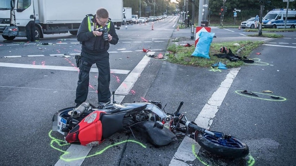 Nach einem Unfall in Leverkusen fotografiert ein Polizist das zerstörte Motorrad.