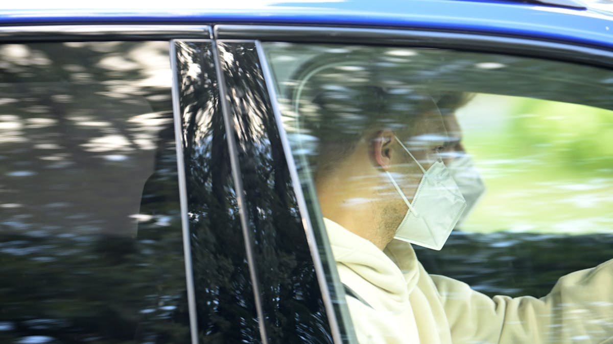 Nationaltorhüter Manuel Neuer sitzt mit Mund-Nasen-Schutz in einem wegfahrenden Auto.