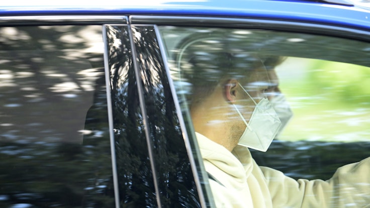 Nationaltorhüter Manuel Neuer sitzt mit Mund-Nasen-Schutz in einem wegfahrenden Auto.