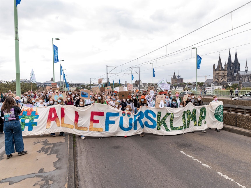 Viele Menschen demonstrieren mit einem Plakat auf der Deutzer Brücke in Köln für Maßnahmen gegen den Klimawandel.